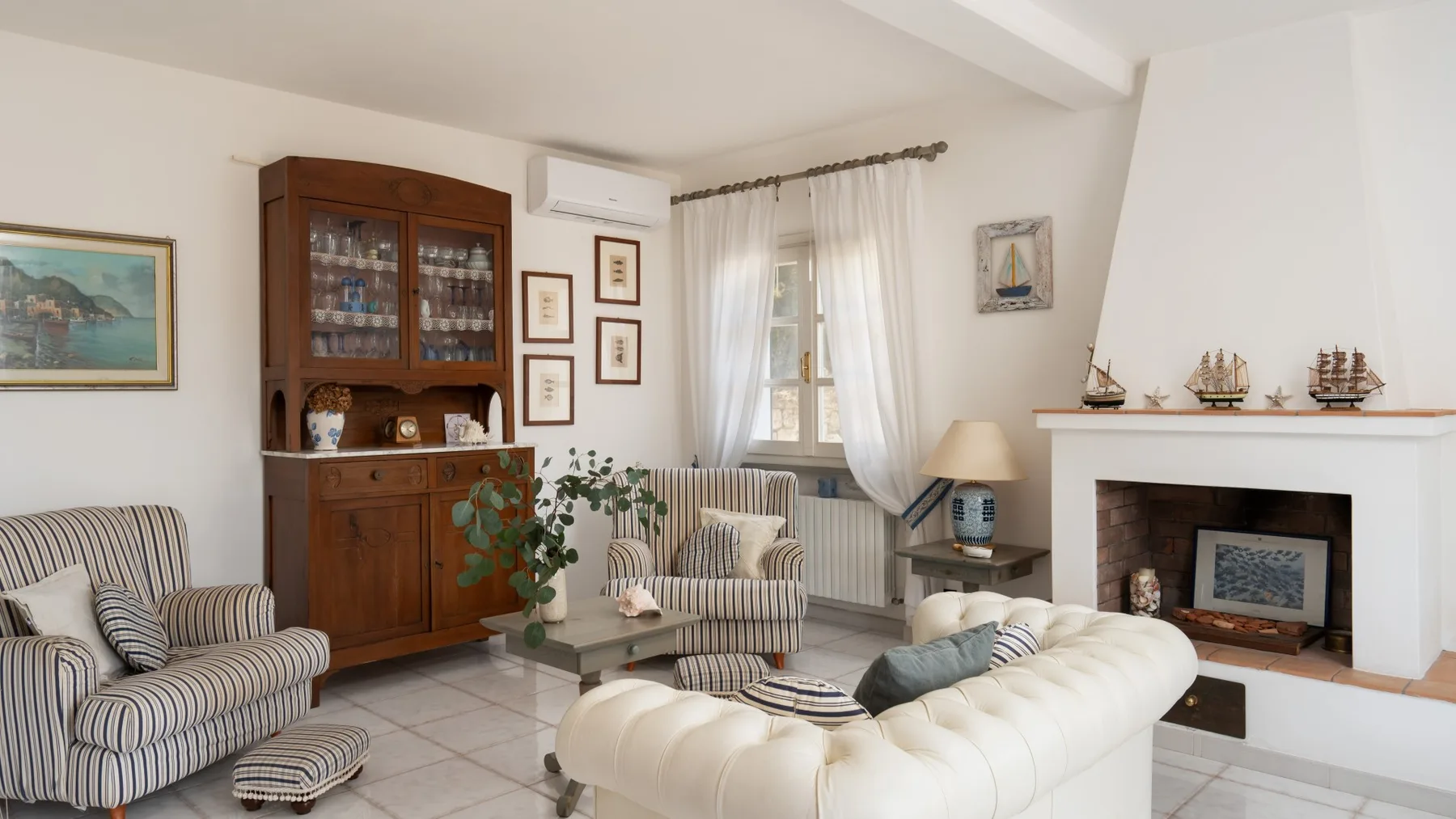 A living room with upholstered seating, a wooden cabinet, and a fireplace.