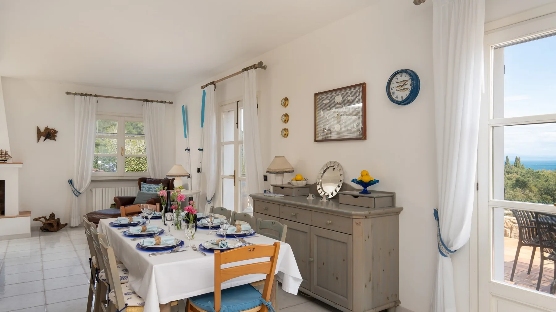 A bright dining room with a set table beside a gray sideboard.