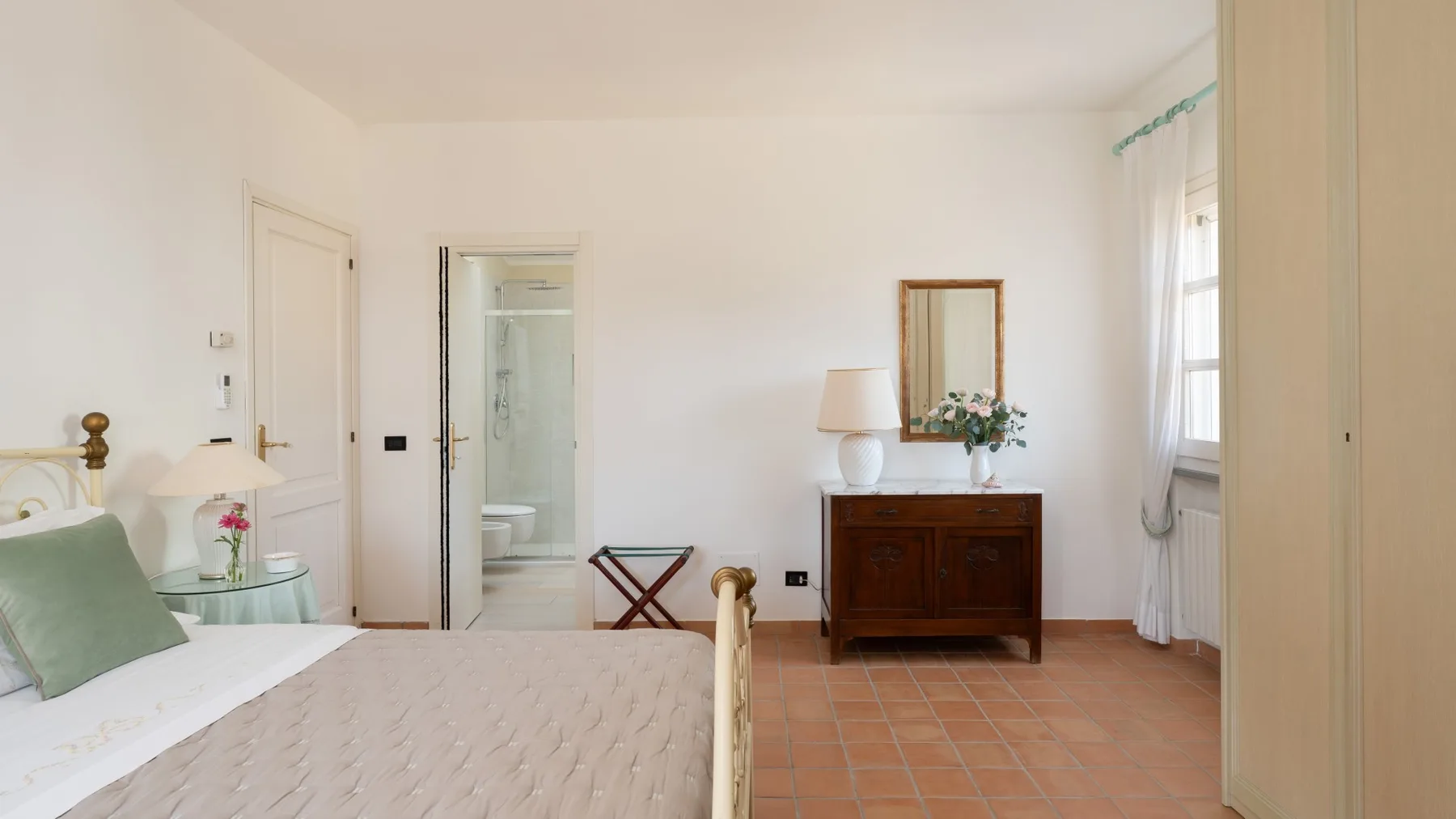 A bedroom with a bed, a wooden dresser, and a doorway to a bathroom.