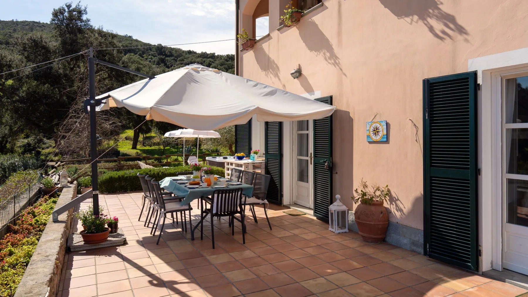 A tiled outdoor patio has a dining table beneath a large shade canopy.