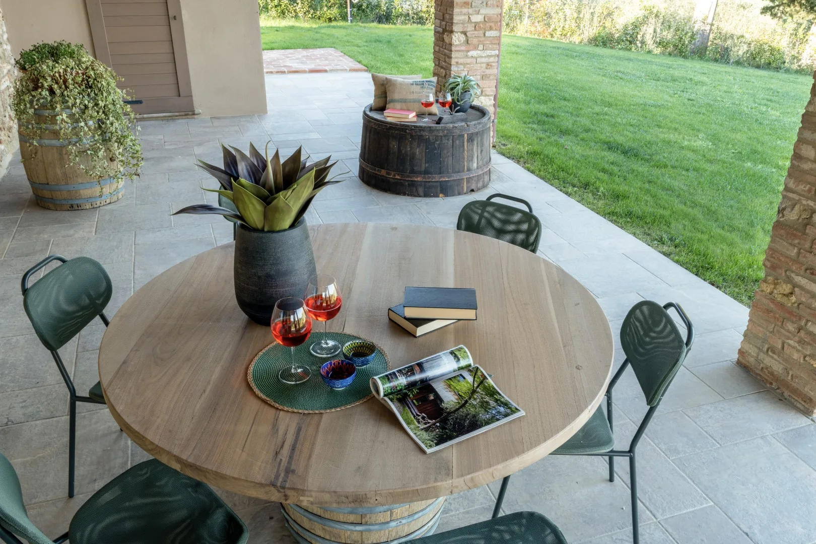 A covered patio dining area with a round table, chairs, and a garden view.