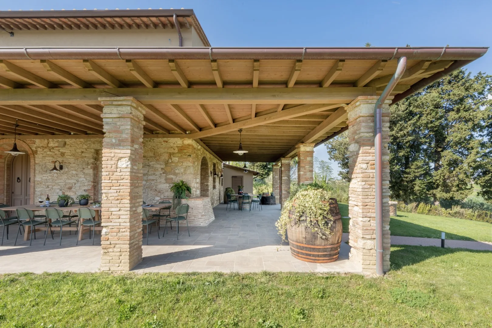 A covered outdoor patio with stone walls, seating, and a grassy garden.