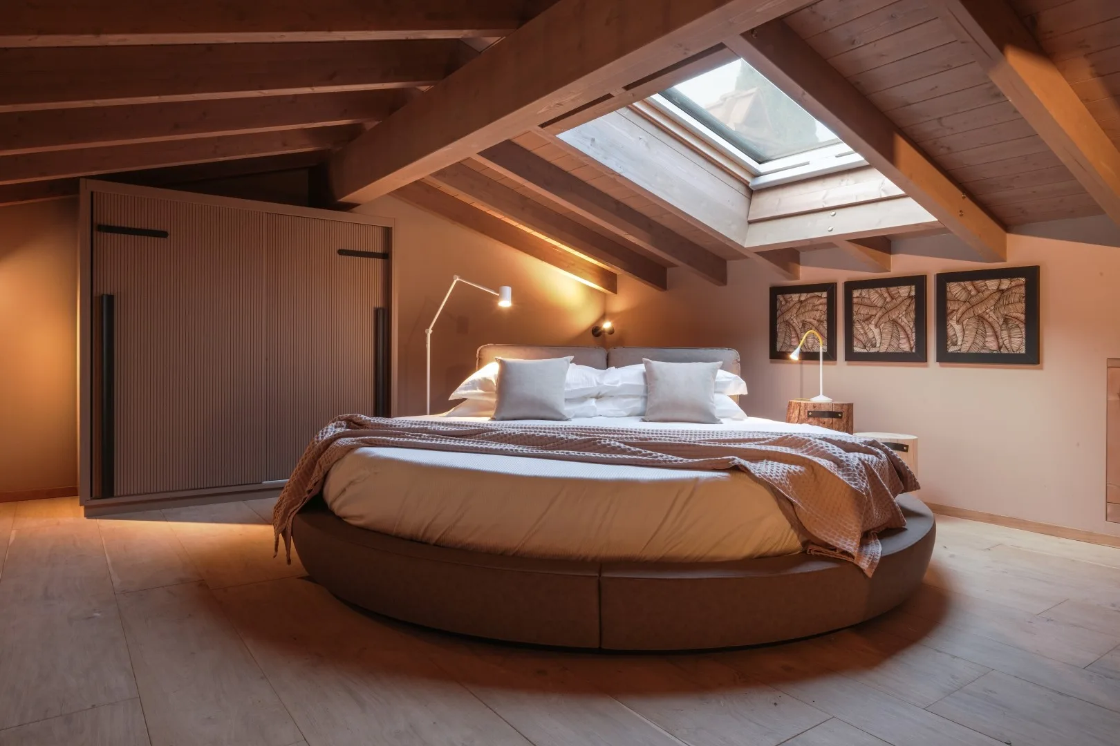 A bedroom with a round bed beneath a large skylight.