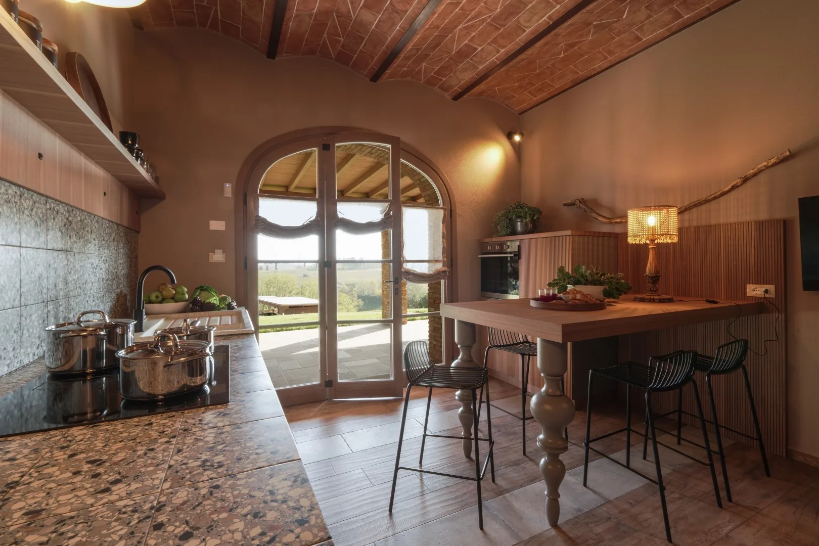 A rustic kitchen and dining area with a central island and glass doors opening outside.