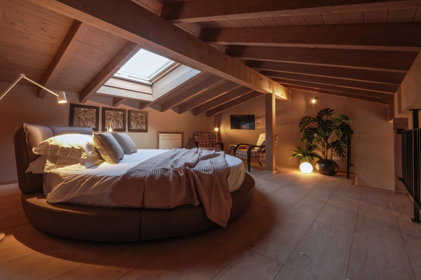 A bedroom with a large bed beneath exposed wooden ceiling beams and a skylight.
