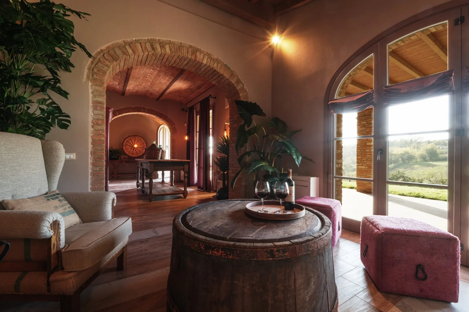 A warm sitting room with an arched brick opening and large windows.