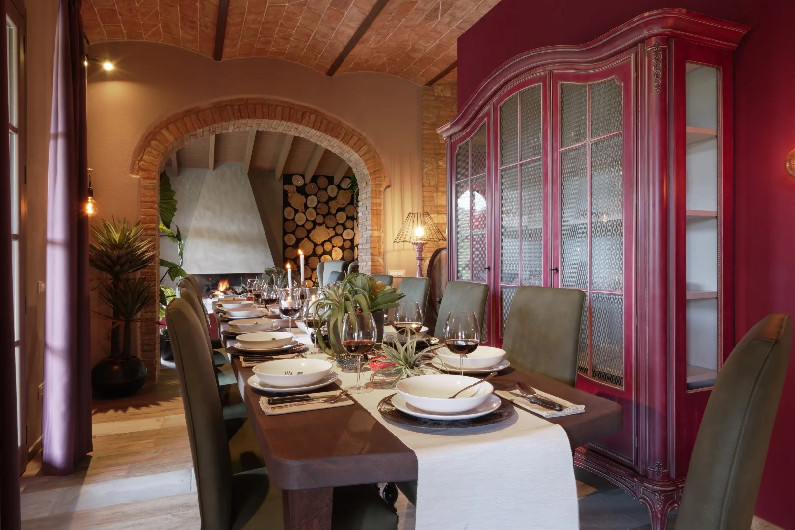 A dining room with a long table set for a meal beneath a brick arch.