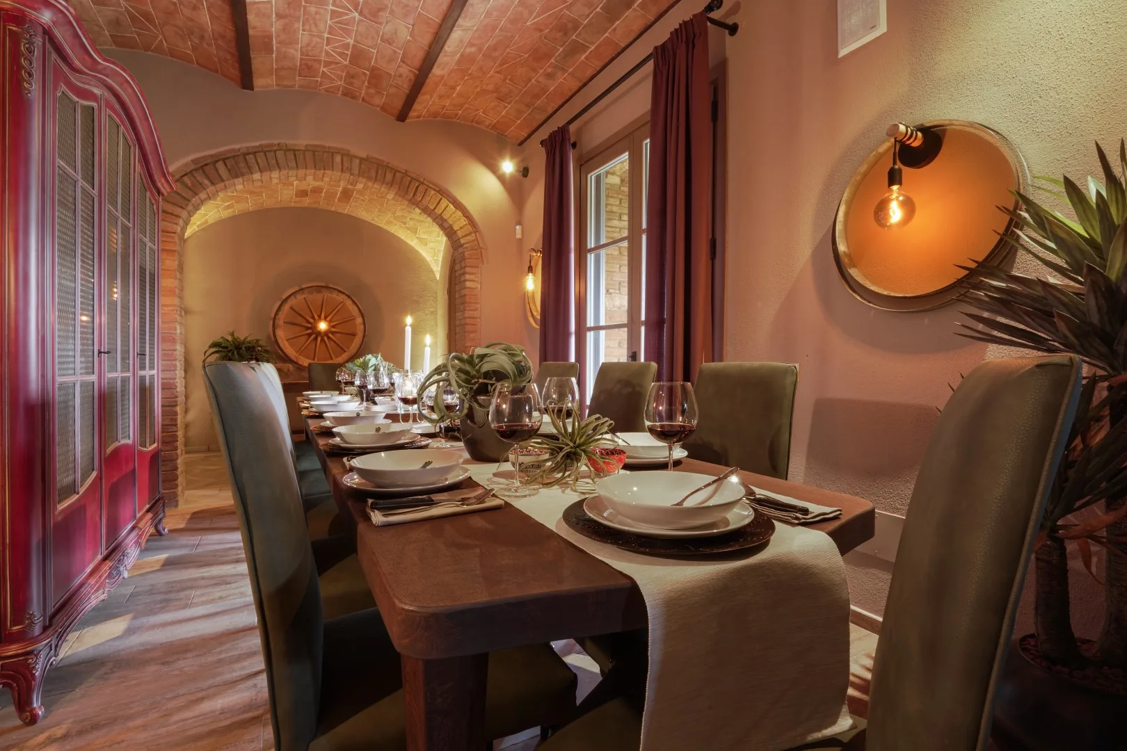 A dining room with a long table set with plates and glassware.