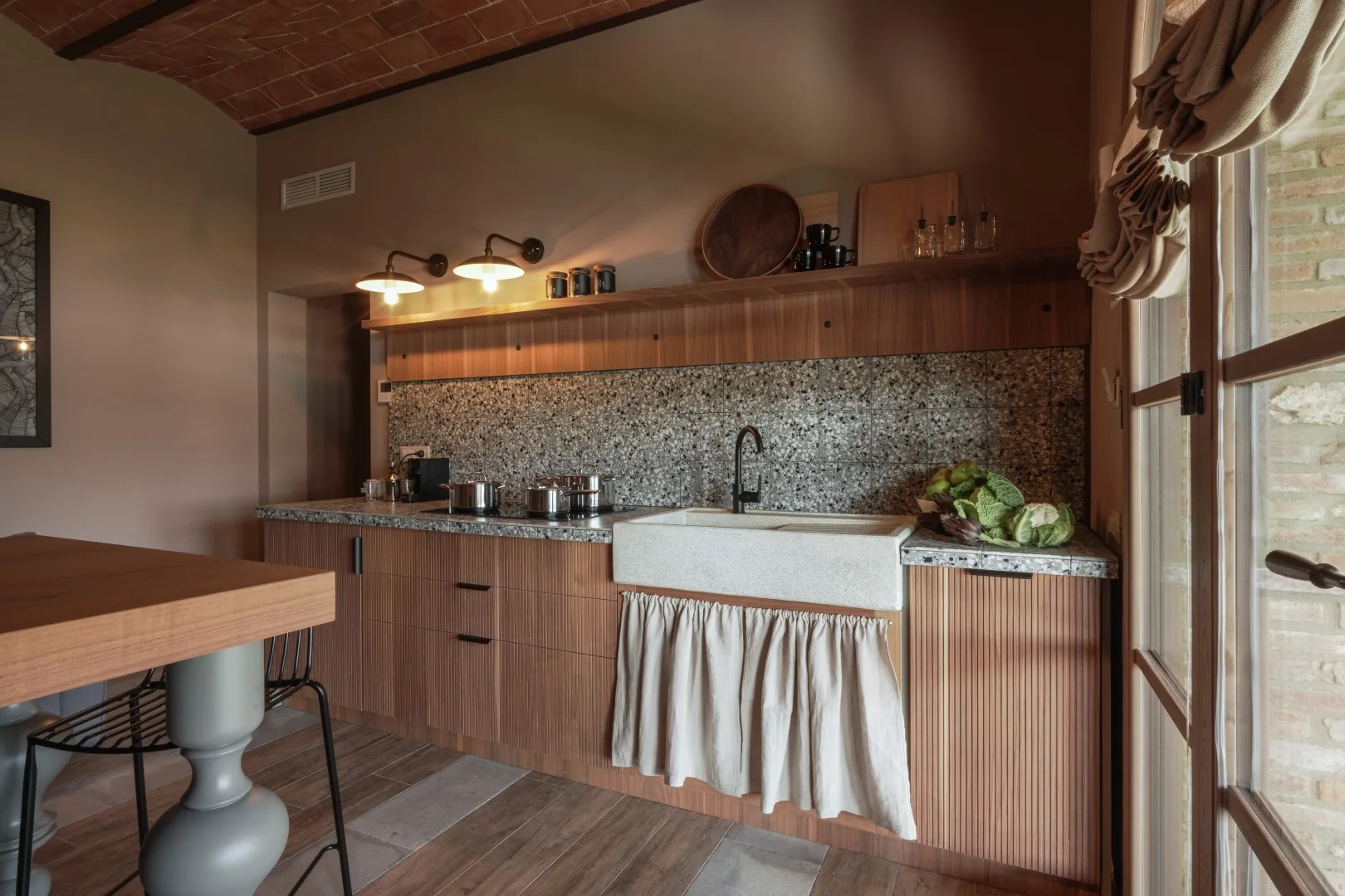 A rustic kitchen with a long counter, sink, and wooden cabinetry.