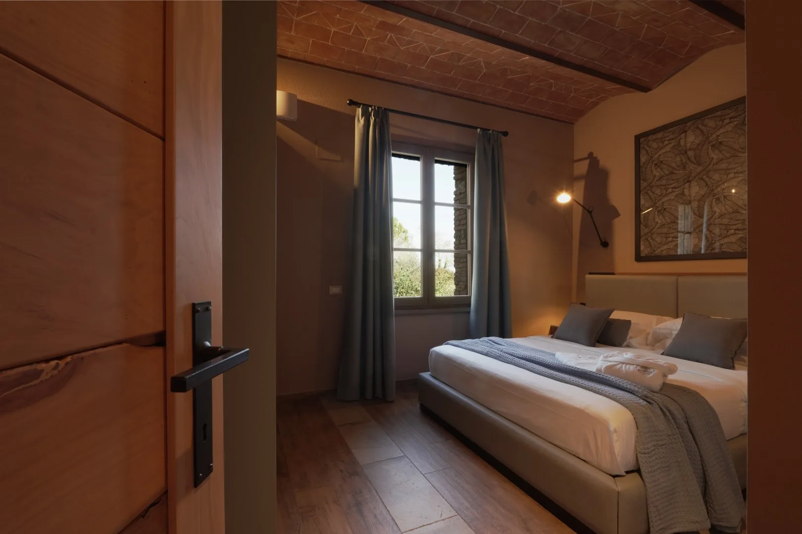 A bedroom with a bed beside a curtained window.
