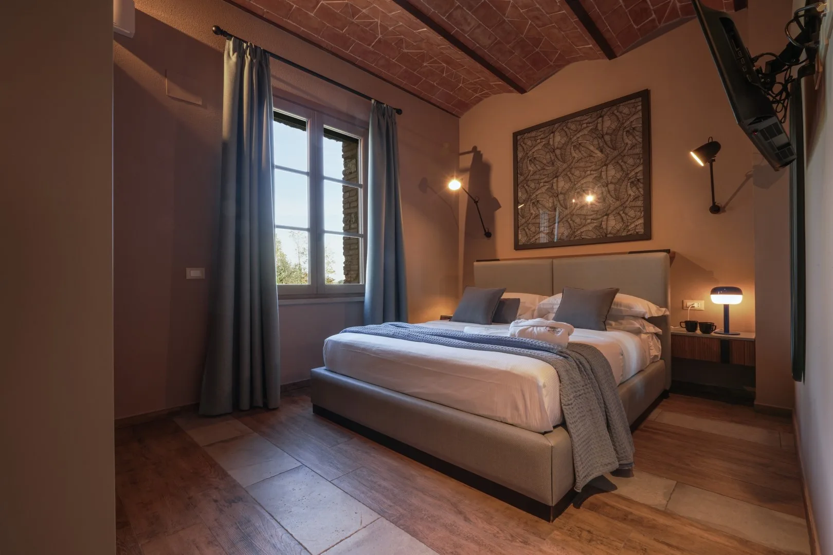 A bedroom with a neatly made bed and a window with curtains.