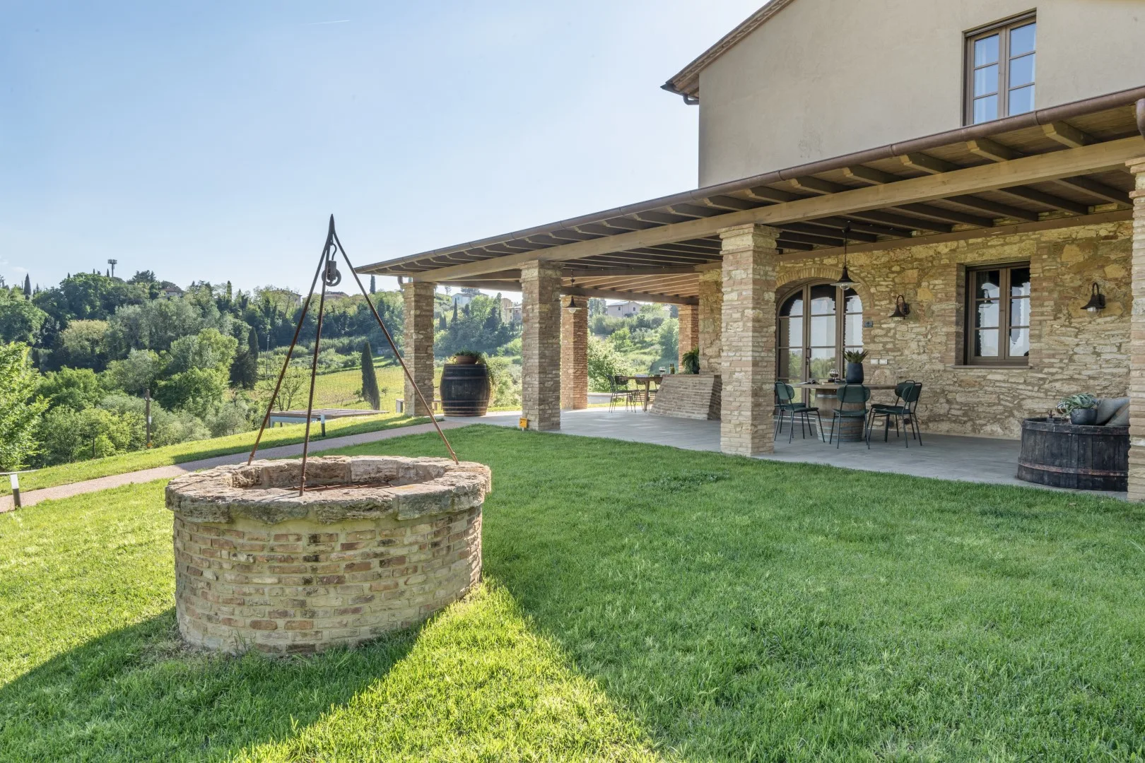 A stone patio overlooks a grassy yard, with a covered seating area beside the house.