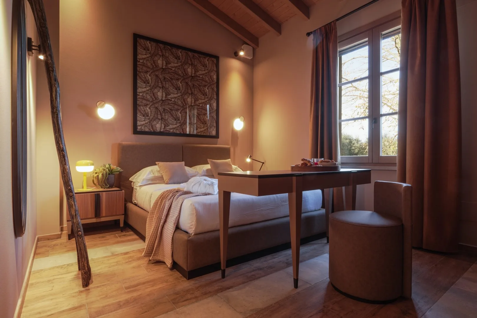 A bedroom with a bed, a desk, and a large window.