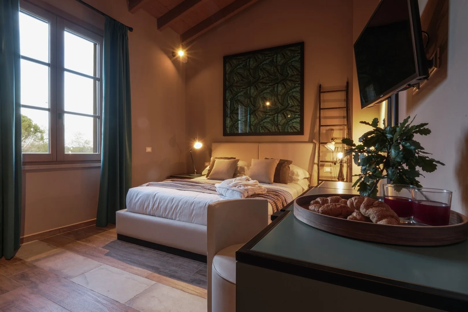 A bedroom with a neatly made bed and large windows.