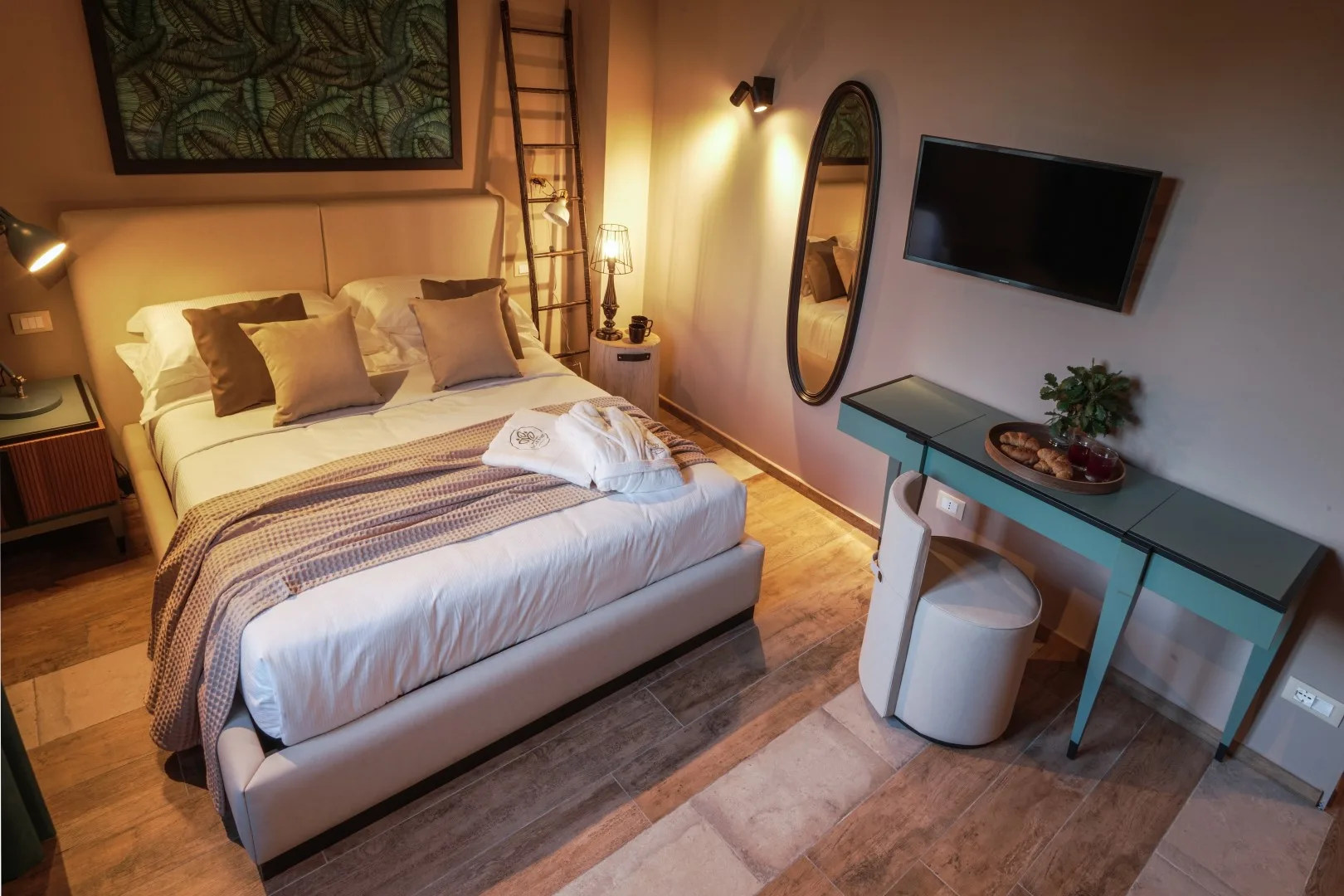 A bedroom with a neatly made bed and a television mounted on the wall.