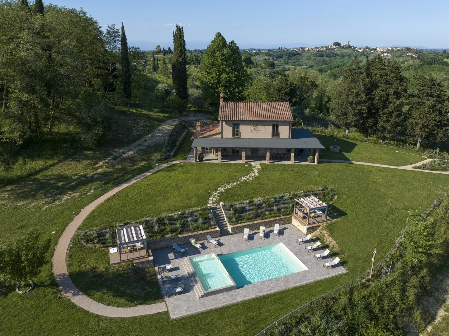 A countryside property with a swimming pool and a two-story house surrounded by greenery.