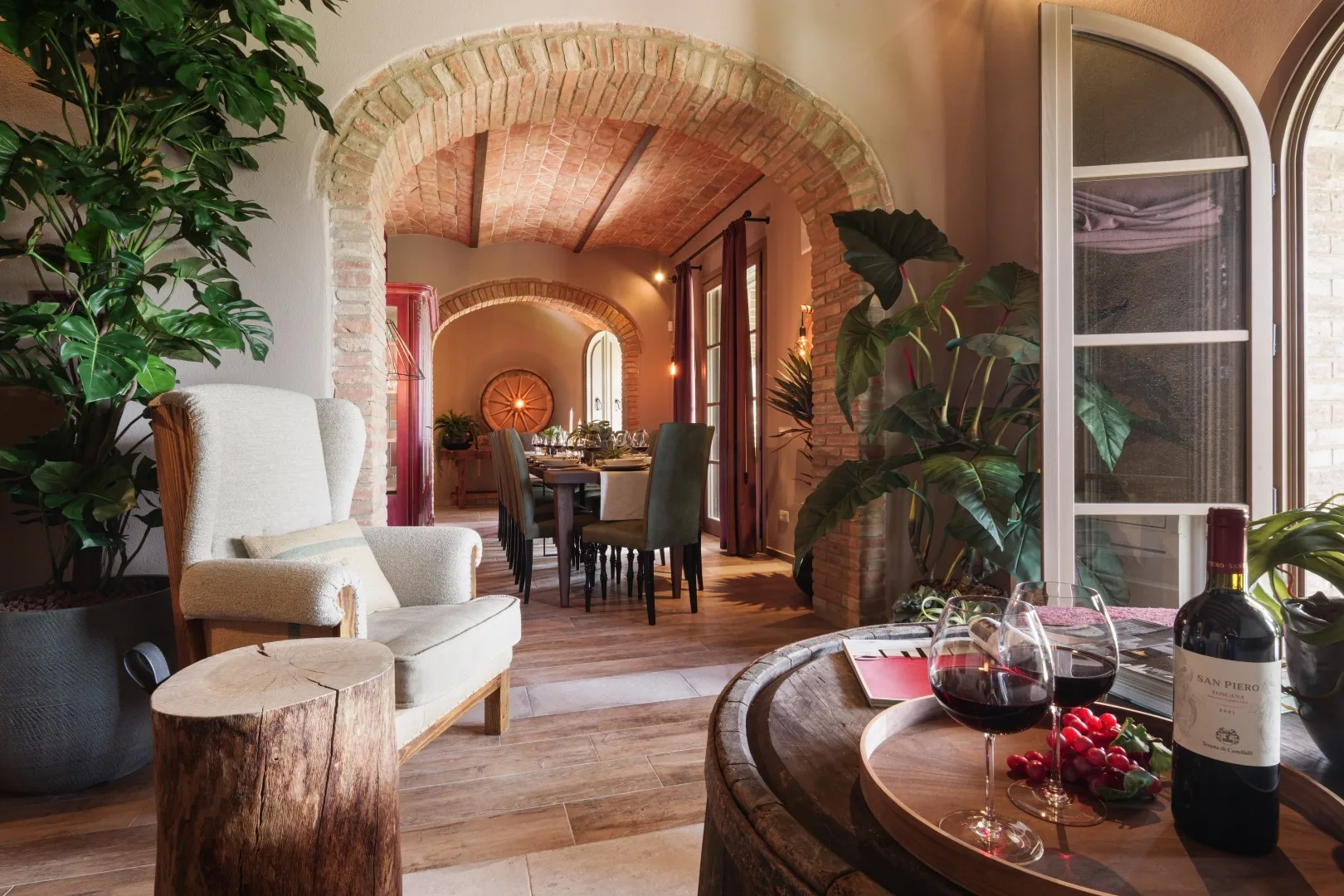 A warm dining room with an arched brick opening and a table set for a meal.