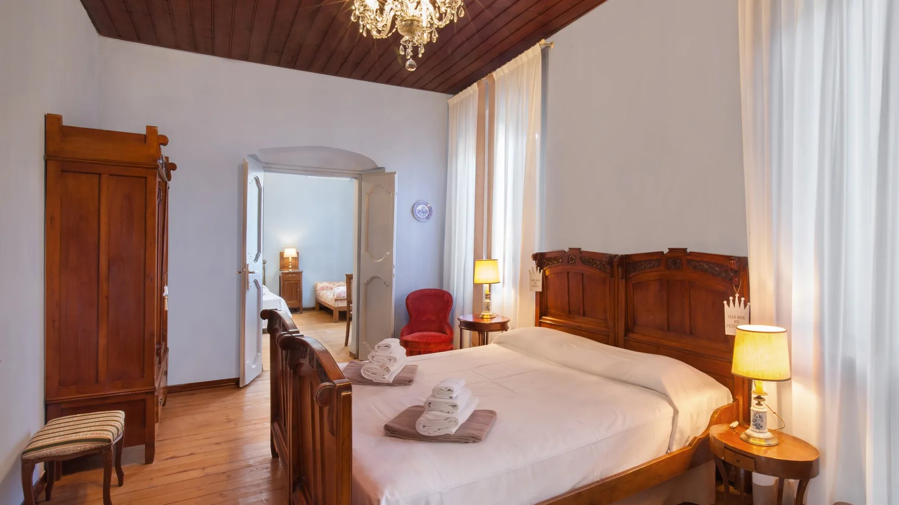 A bedroom with a wooden bed, bedside tables, and tall curtained windows.