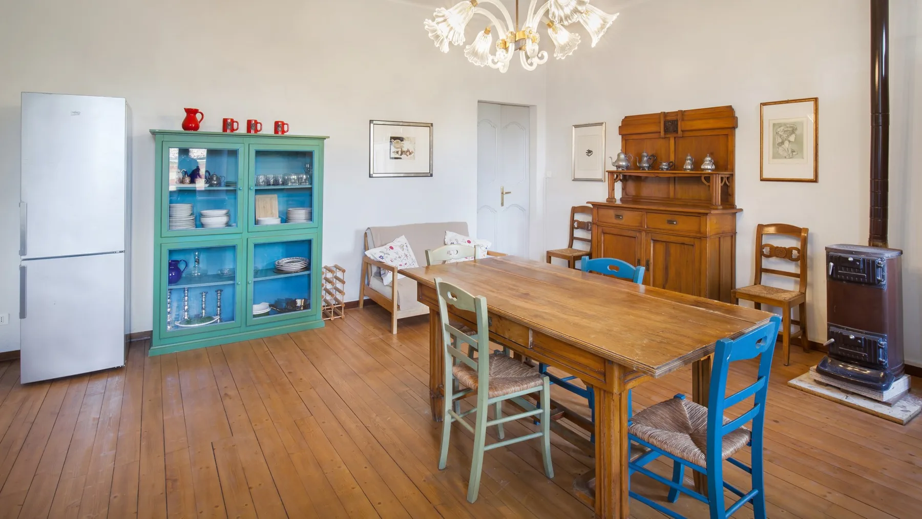 A dining room with a long wooden table and colorful chairs.