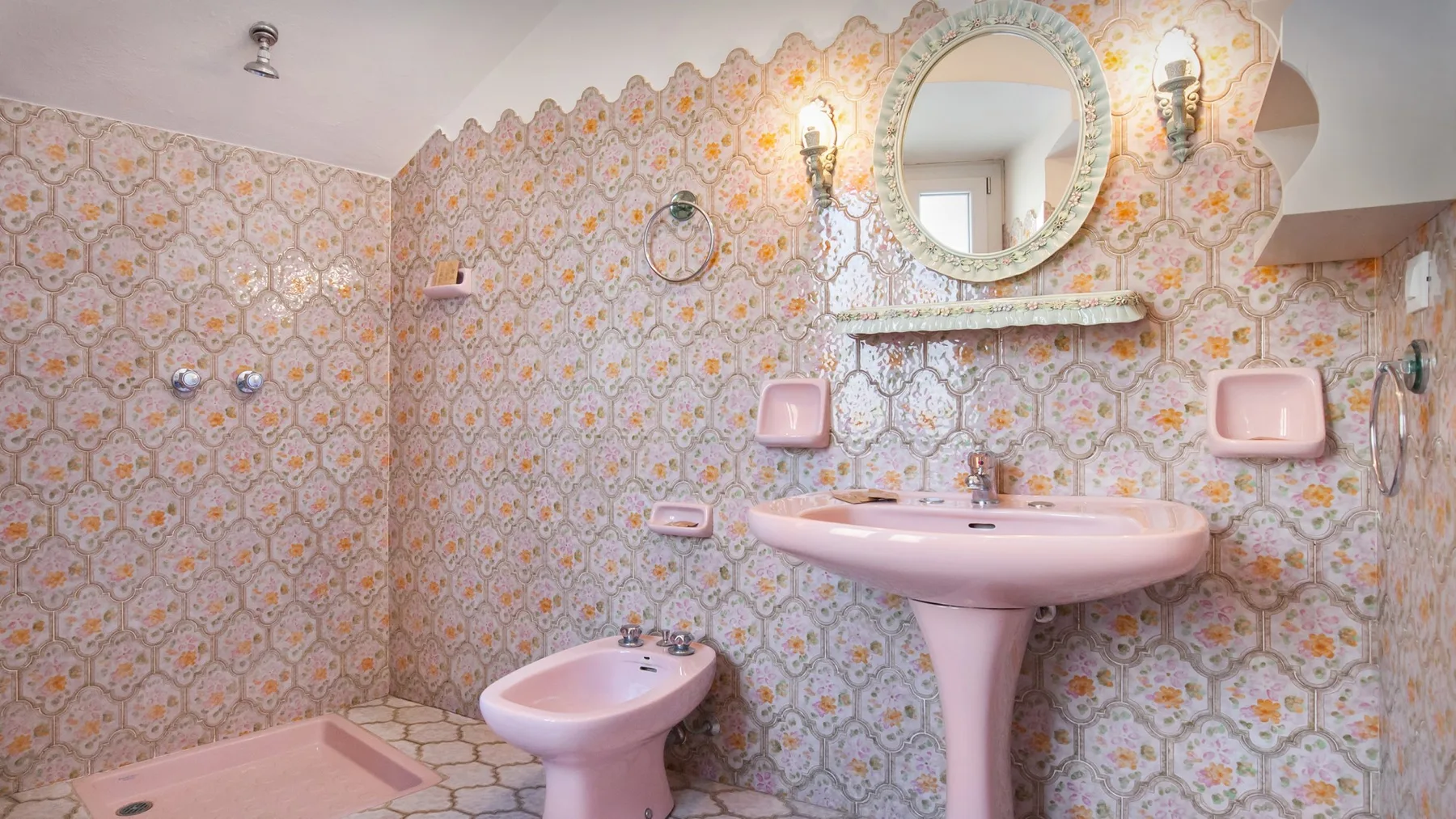 A bathroom with a pink sink, toilet, and patterned walls.