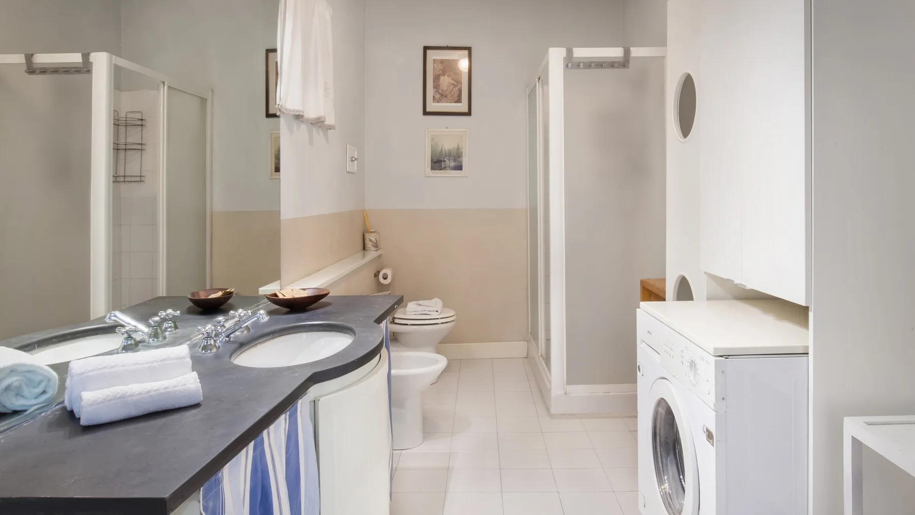 A bathroom with a sink vanity, toilet, and washing machine.
