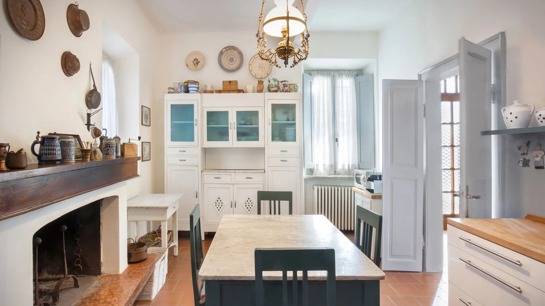 A bright dining room with a long table, a fireplace, and white cabinetry.