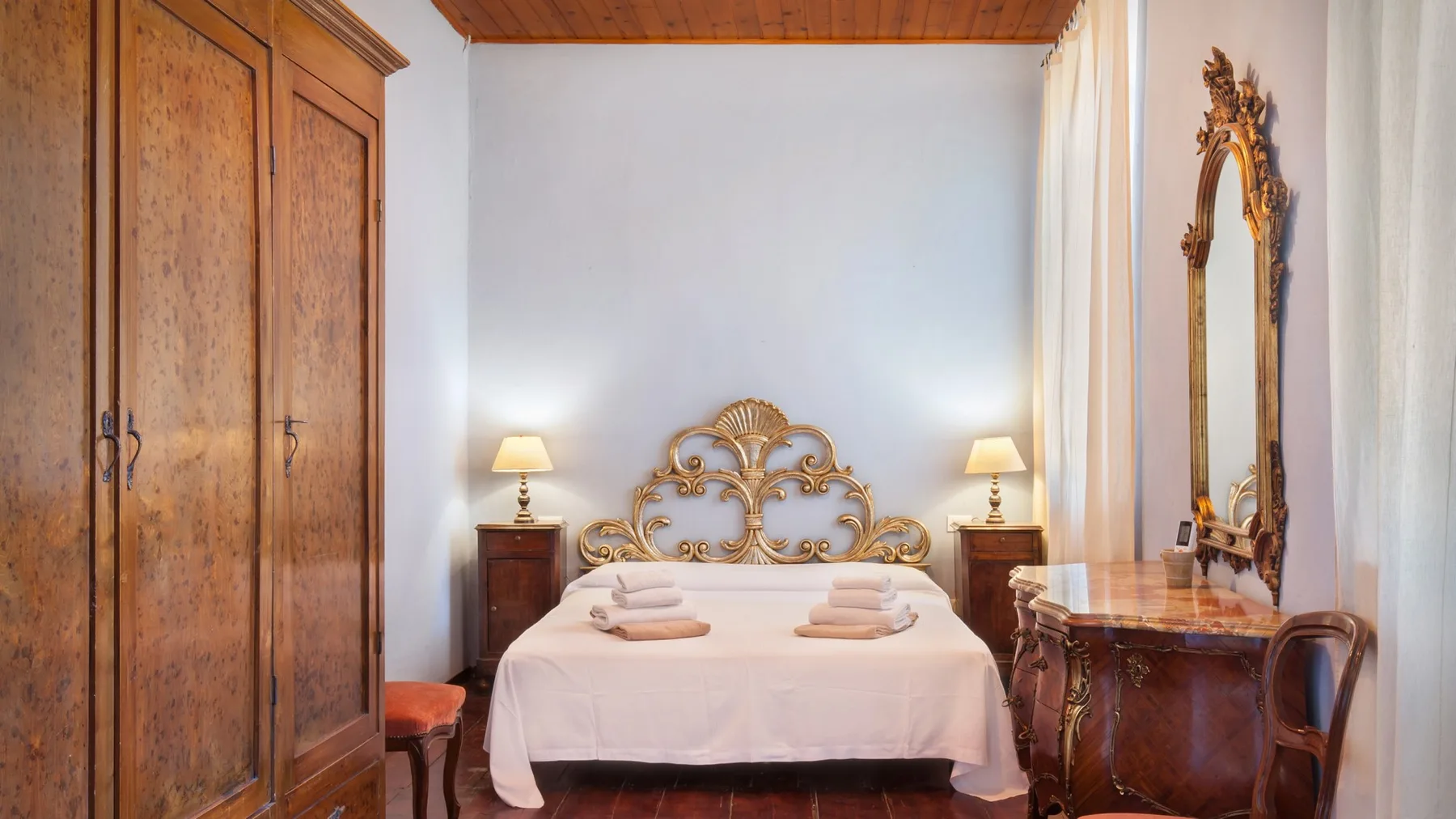 A bedroom with a bed, bedside tables, and a wardrobe.