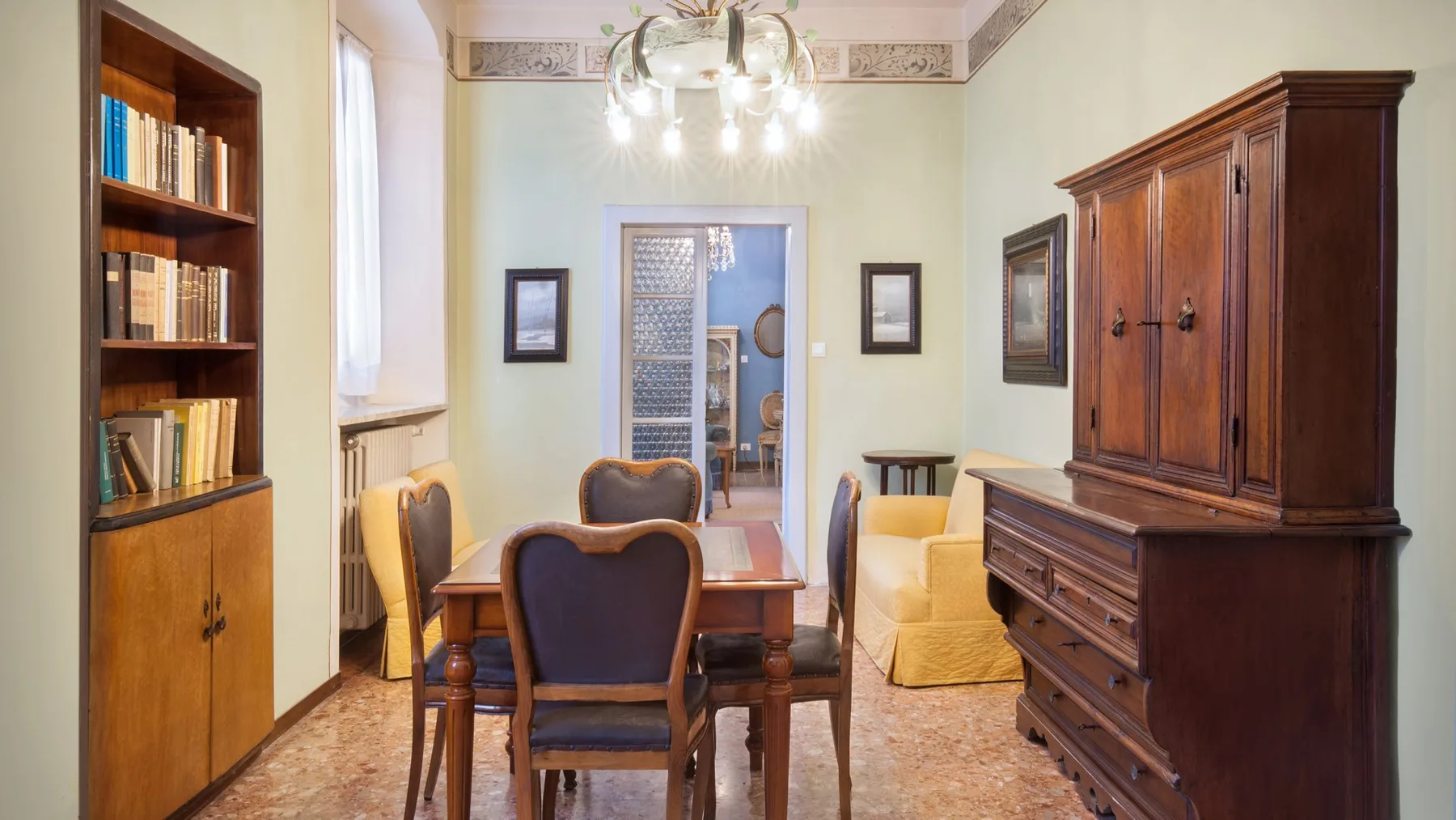 A dining room with a wooden table, surrounding seating, and a large cabinet.
