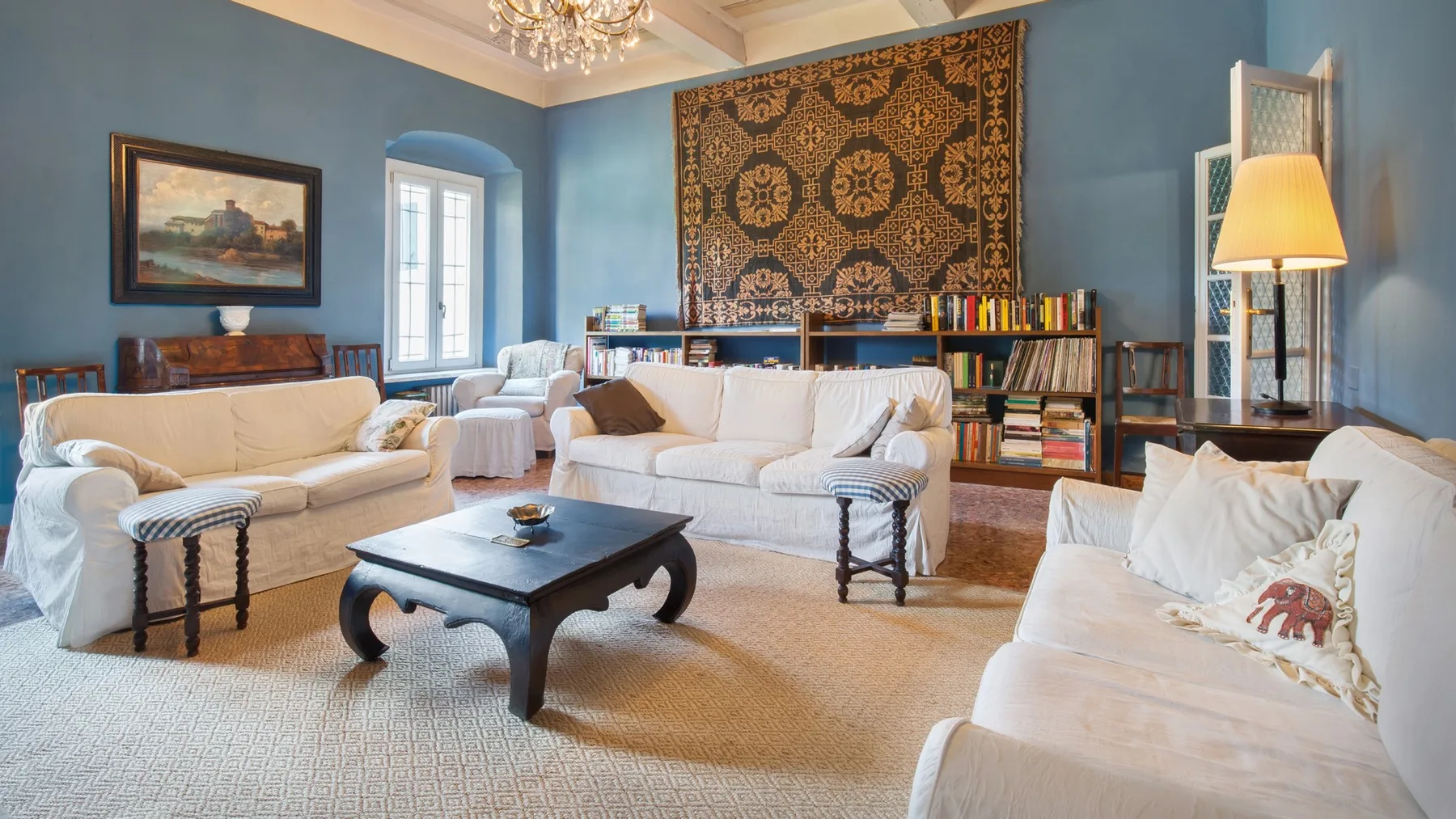 A living room with white seating, a dark coffee table, and bookshelves.