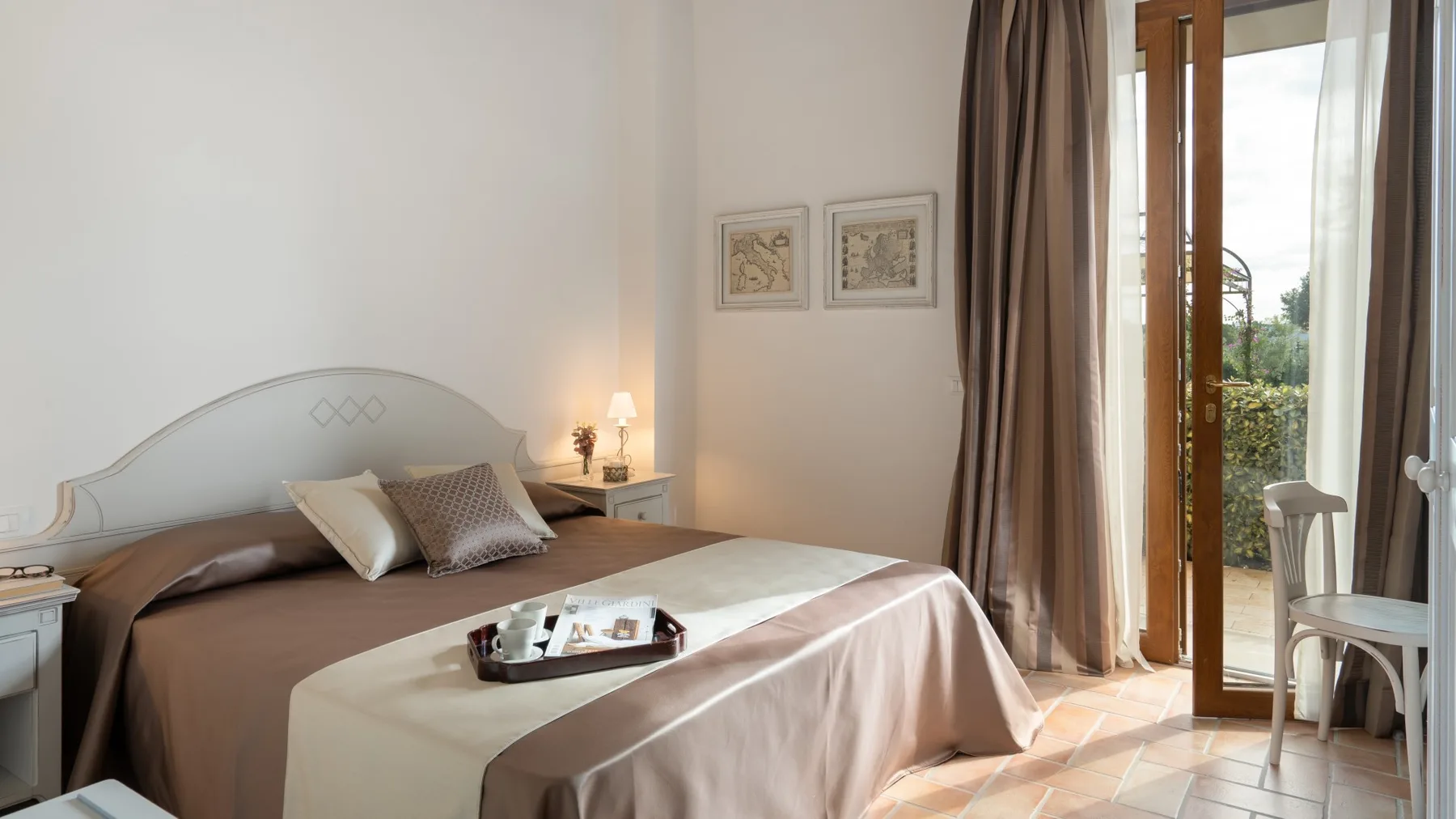 A bedroom with a neatly made bed and open doors leading to a balcony.