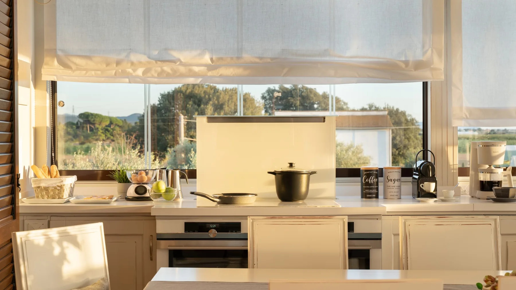 A bright kitchen with a wide window and a pot on the cooktop.