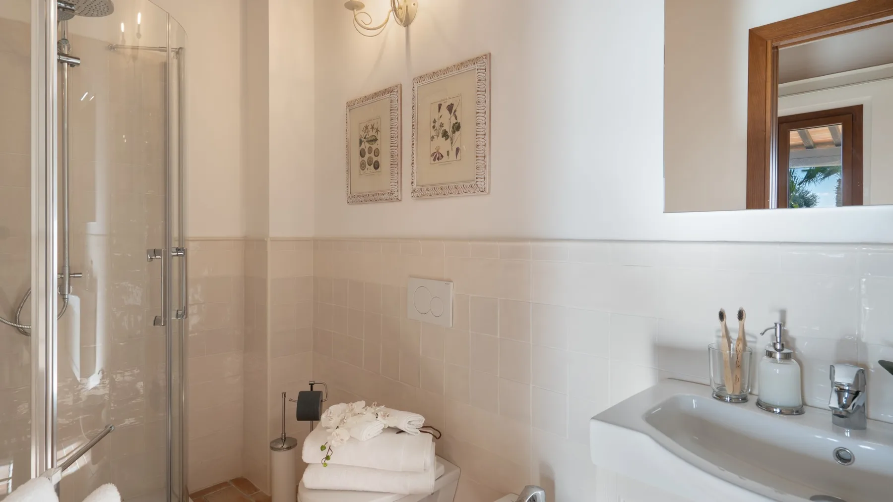 A bathroom with a glass shower and a sink topped with toiletries.