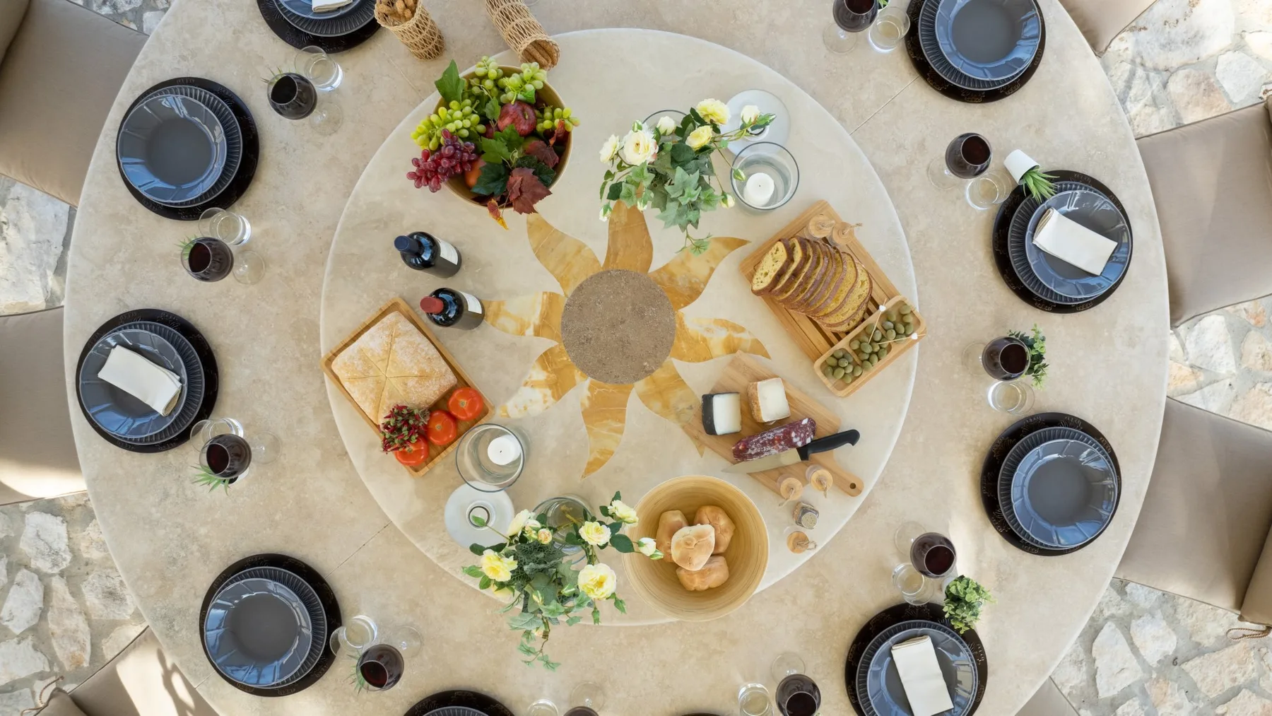 A round dining table is set with plates, drinks, and assorted food.