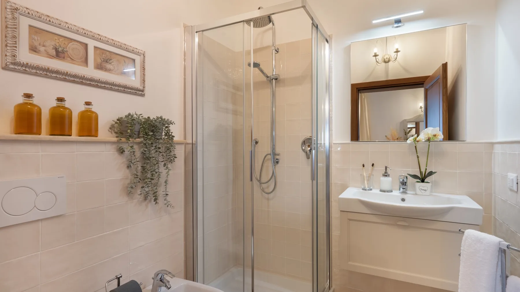 A bathroom with a glass shower and a sink beneath a mirror.