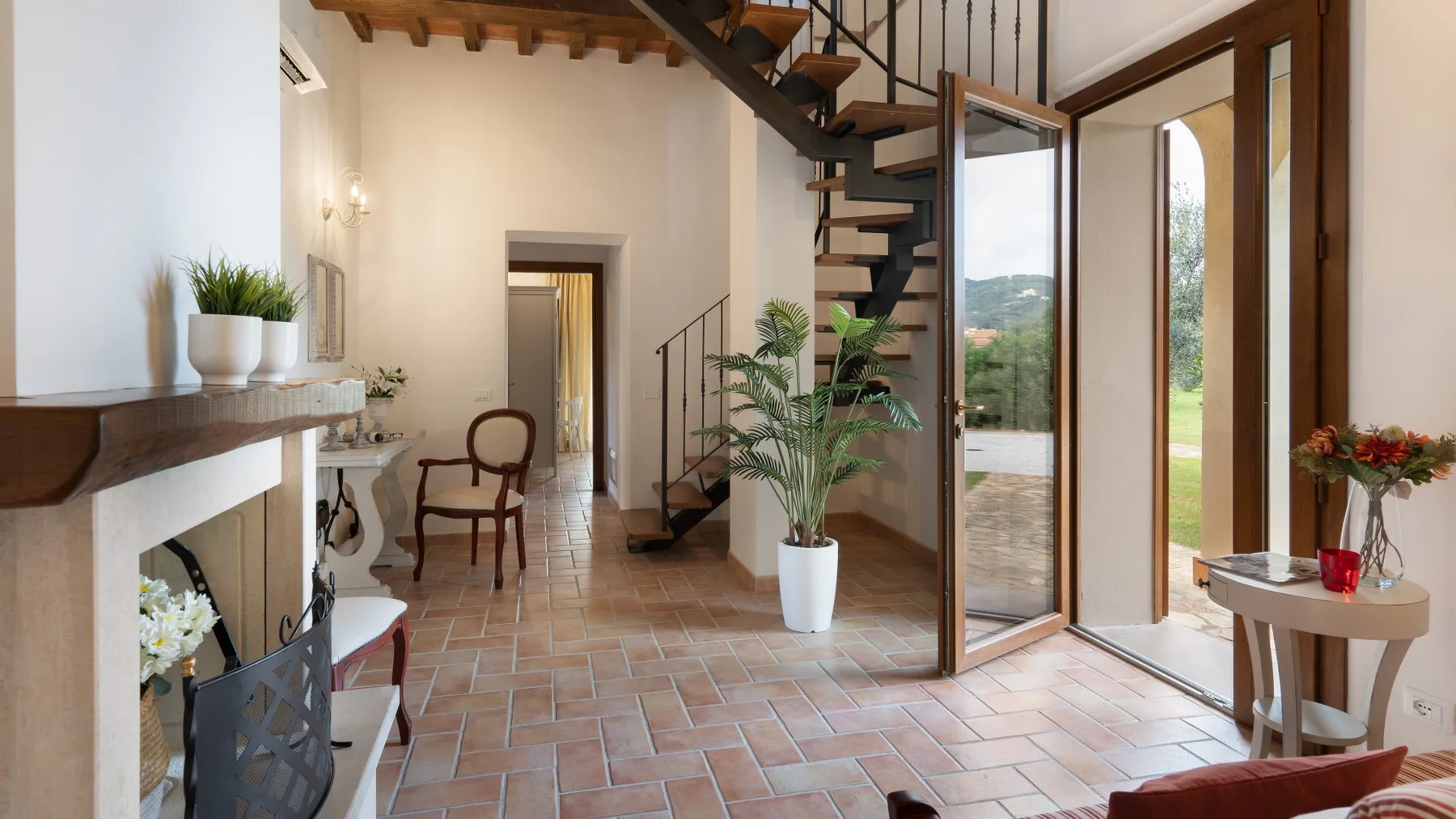 A bright living room with a tiled floor, fireplace, and open staircase.