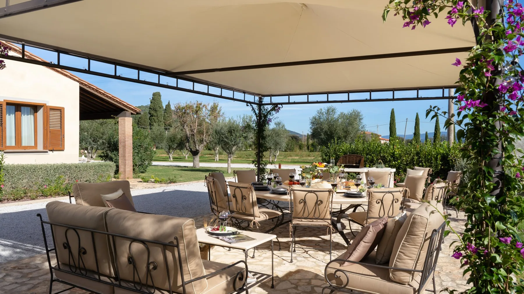 An outdoor dining area under a canopy, with cushioned seating around a table.