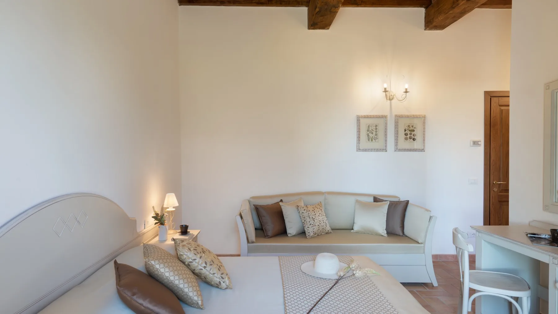 A bedroom with a bed, a sofa, and a small dining area.