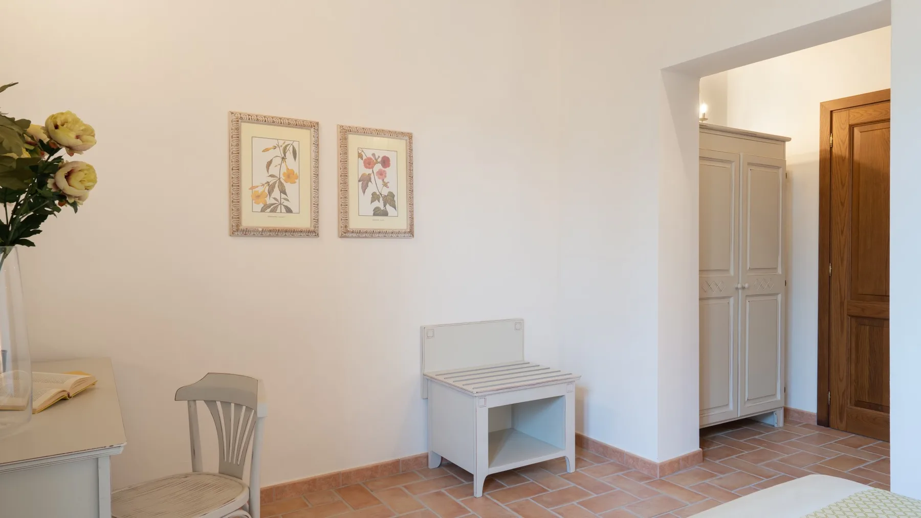 A bright room with framed botanical prints and a small white table.