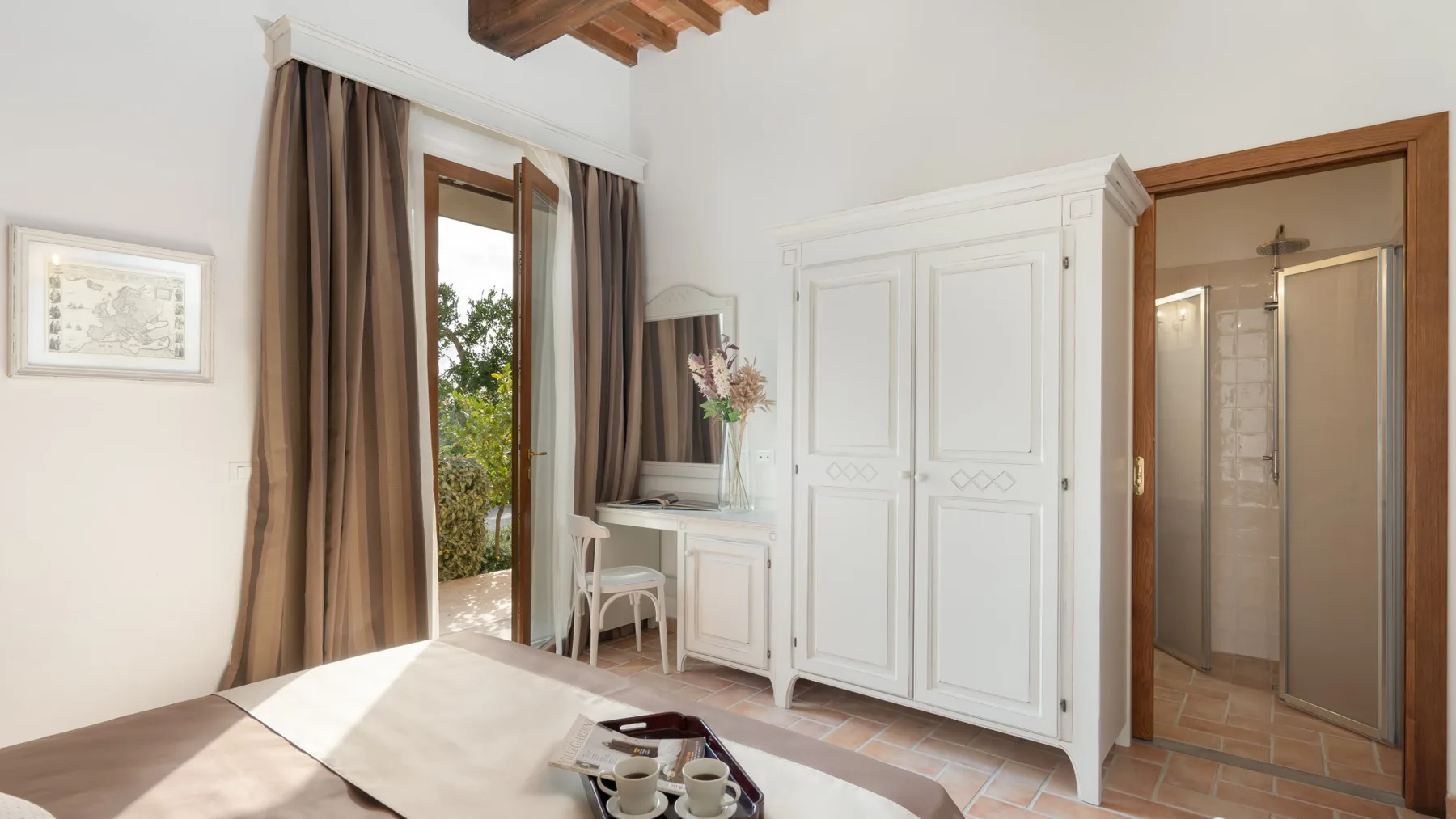 A bright bedroom with a white wardrobe and an open doorway to a bathroom.
