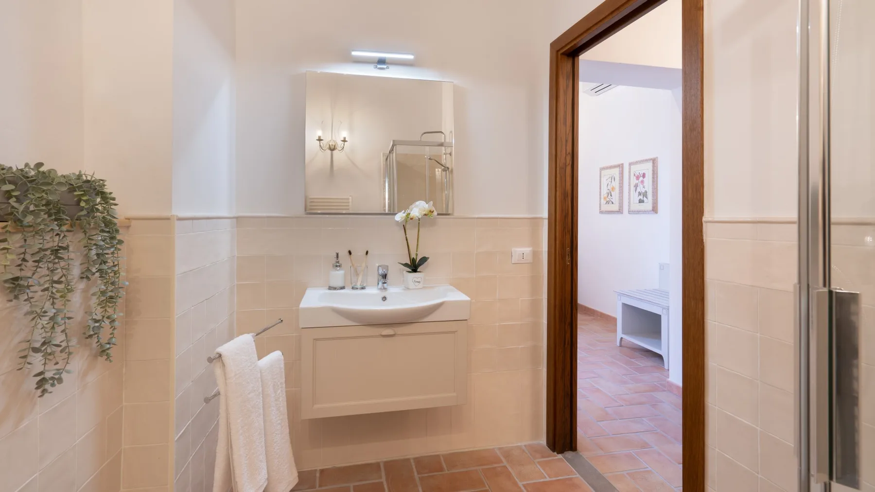 A bright bathroom with a wall-mounted sink and a doorway opening to another room.