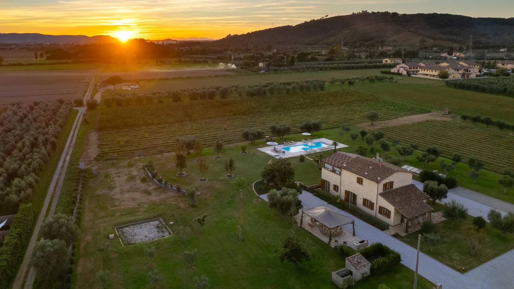 Aerial view of a countryside property and surrounding fields at sunset.