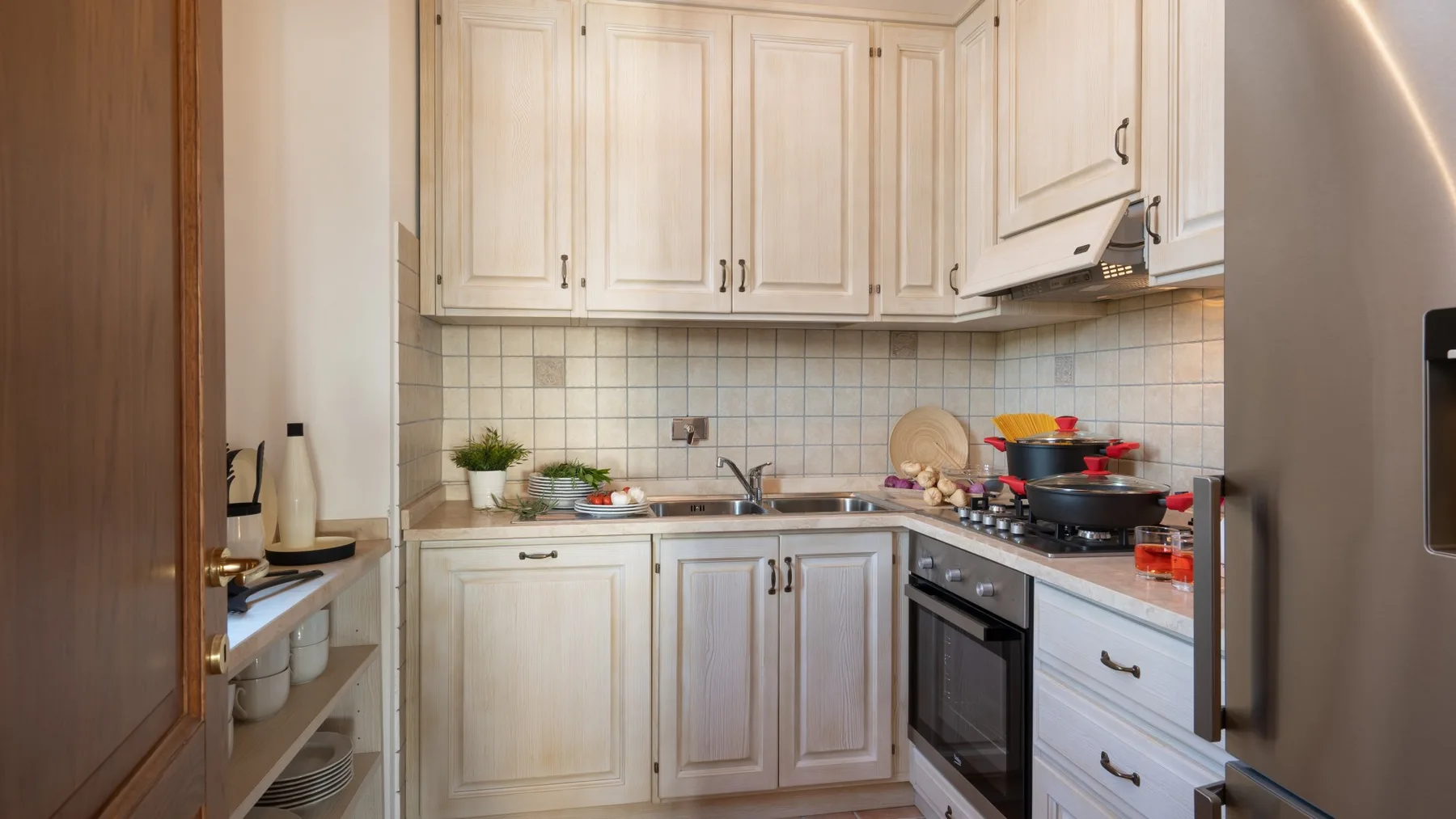 A compact kitchen with pale cabinets, a sink, and a stove.