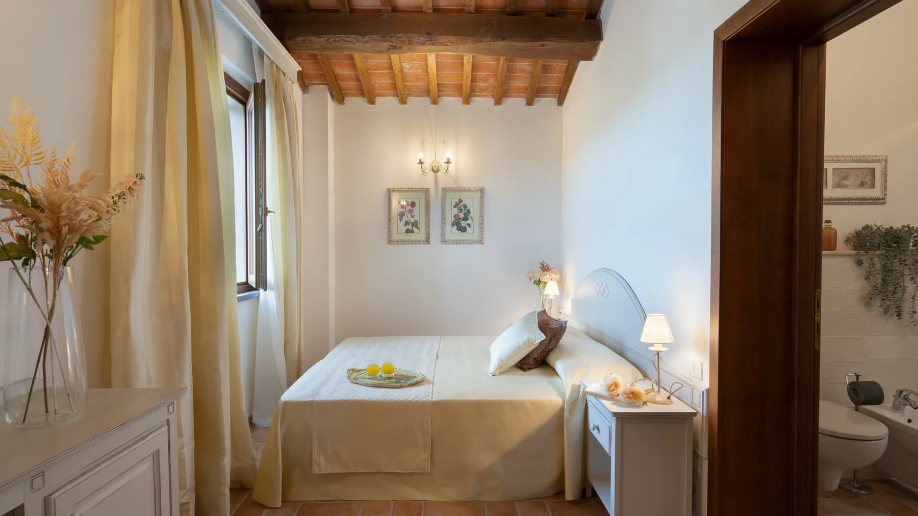 A bedroom with a bed, bedside table, and exposed wooden ceiling beams.