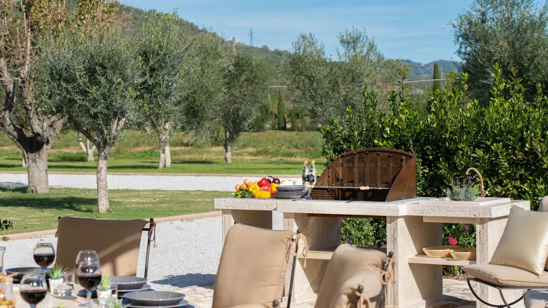 An outdoor patio dining area overlooks a landscaped garden with trees and greenery.