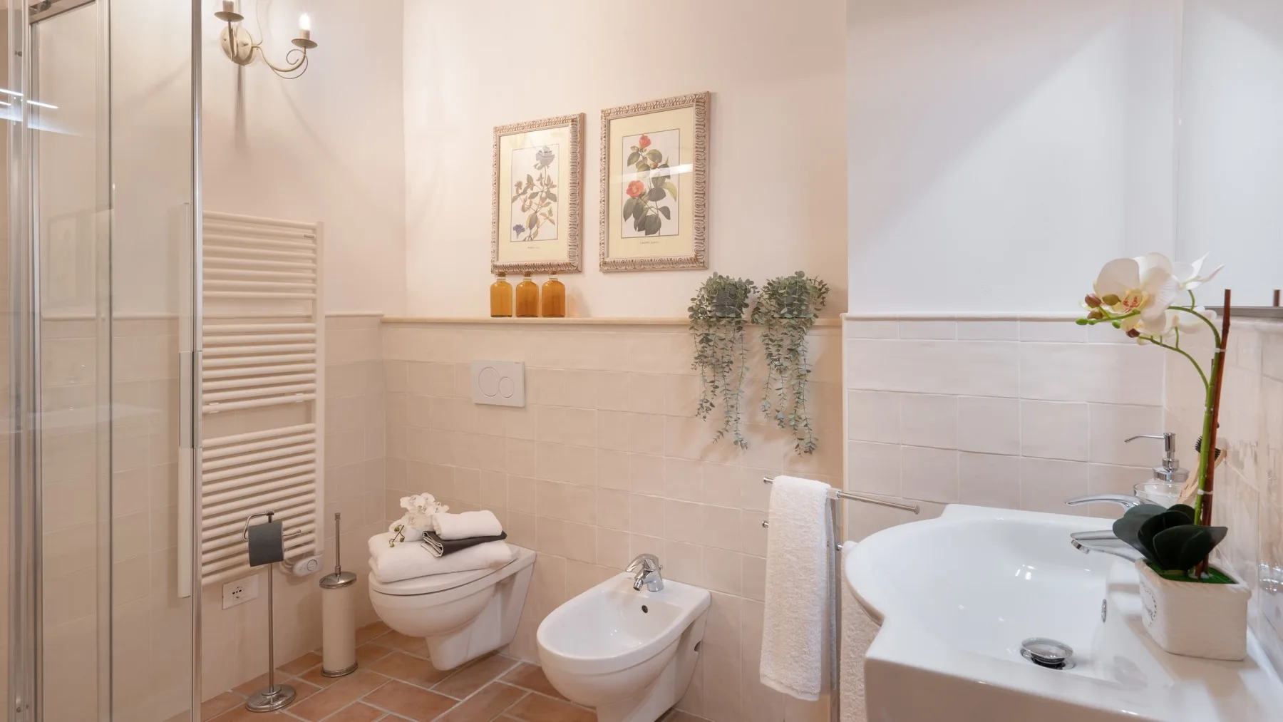 A bright bathroom with a glass shower, toilet, bidet, and bathtub.