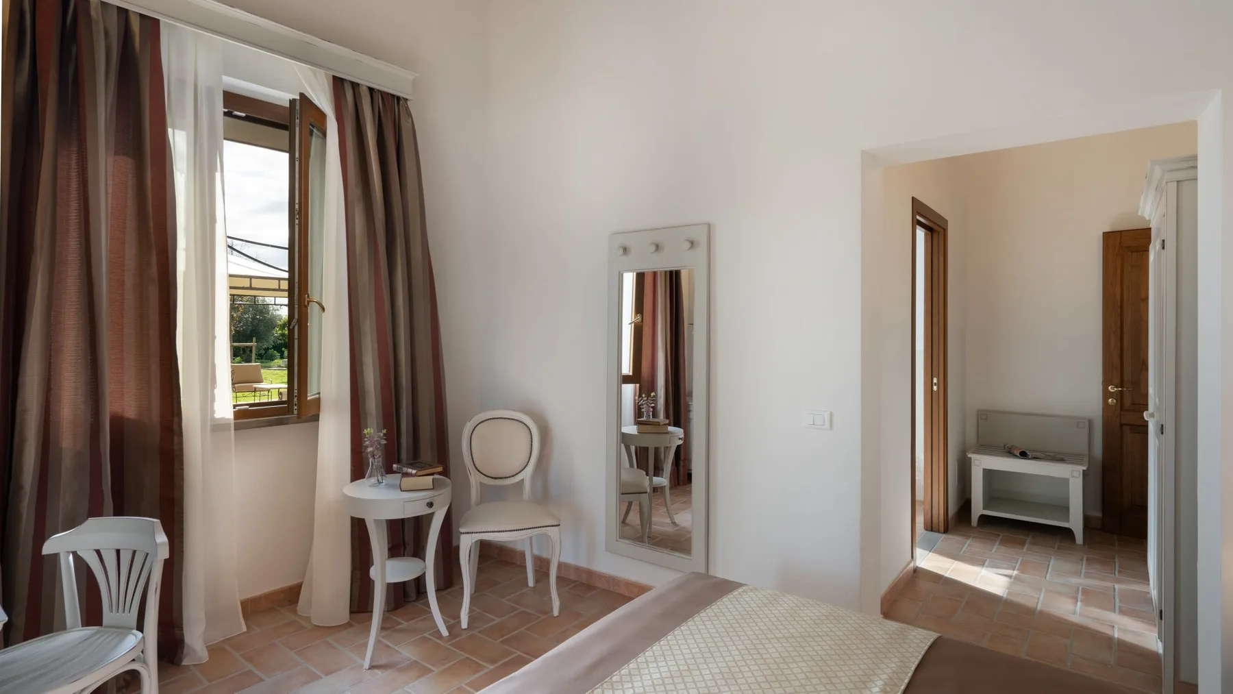 A bright room with a window, seating, and a doorway to an adjoining space.