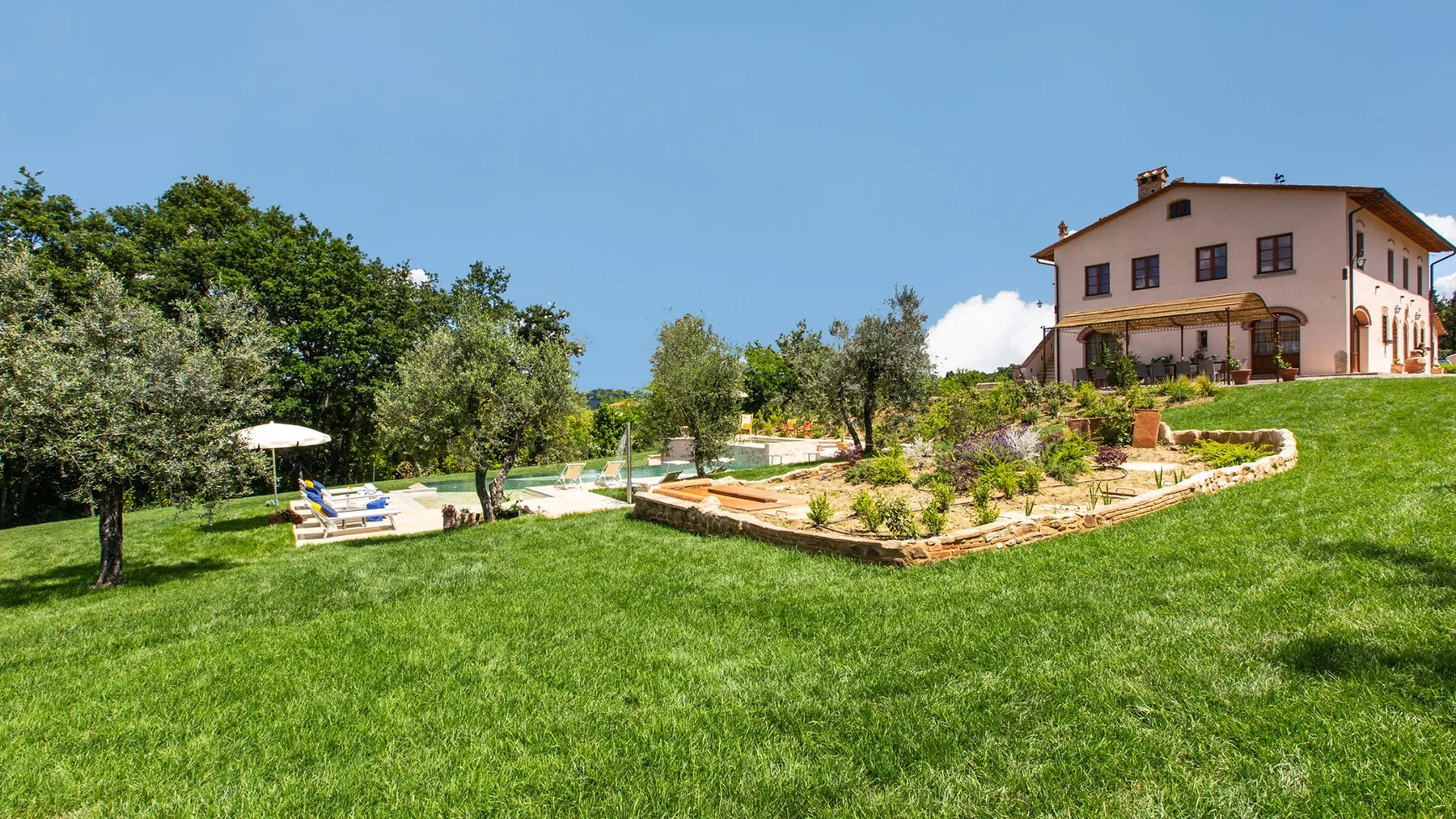 A landscaped garden surrounds a house, with a swimming pool and lawn.