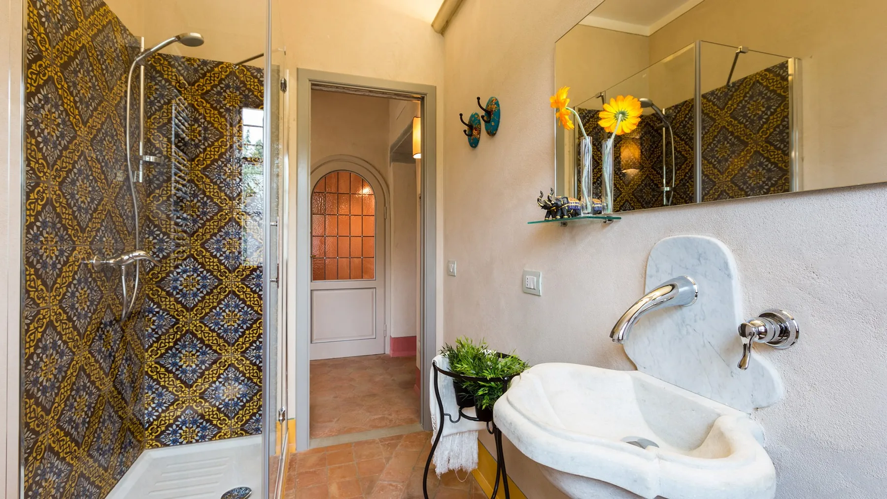 A bathroom with a patterned shower area and a white basin.