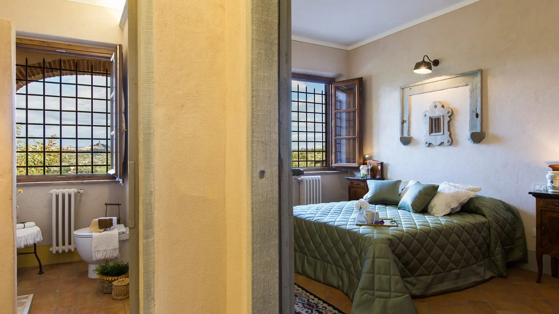 A bedroom with a bed beneath an open window and a framed wall mirror.