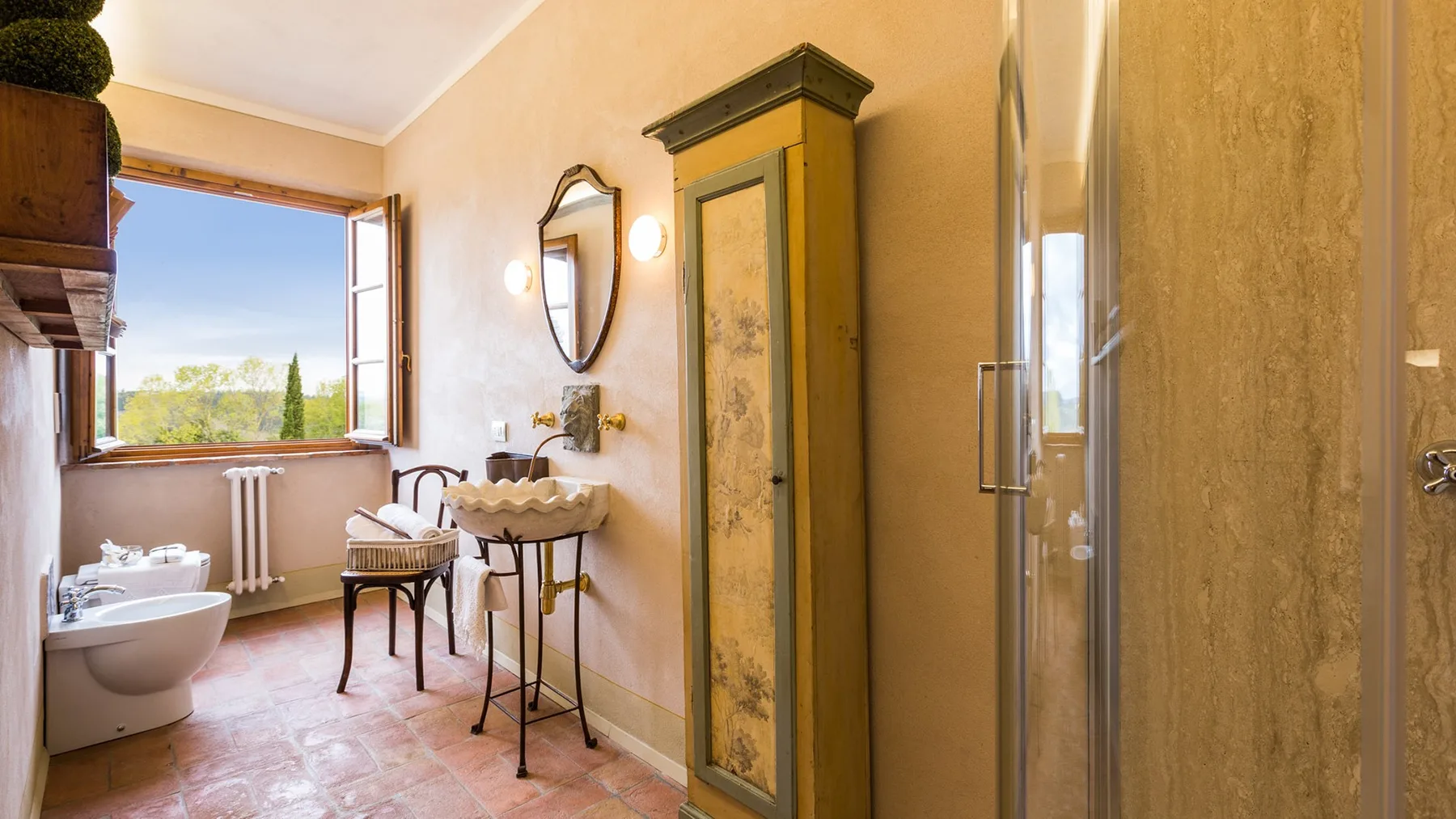 A bathroom with a sink, toilet, and shower beside a window.